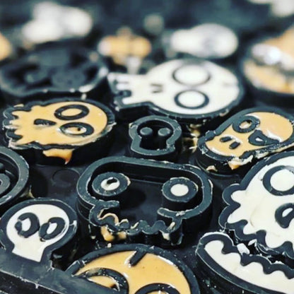 Up close image of a black enrichment lick mat for dogs with skull designs. The skull designs are filled with peanut butter and greek yoghurt.